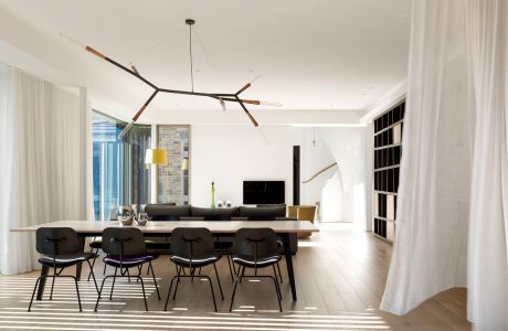 Minimalist dining room with modern light fixture, textured walls, and striped flooring.