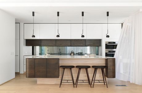 Modern kitchen with clean lines, dark wood cabinetry, pendant lighting, and sleek bar stools.