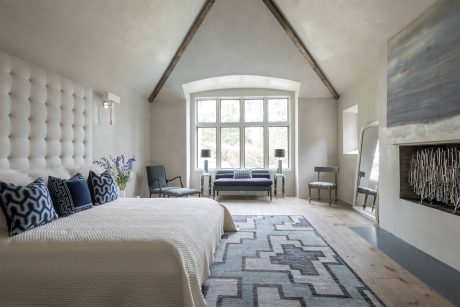 A luxurious bedroom with high ceilings, arched windows, and a plush tufted headboard.