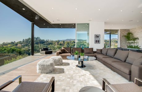 Spacious modern living room with floor-to-ceiling windows, sleek furnishings, and scenic mountain view.