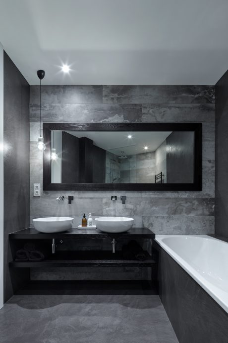 A sleek, modern bathroom with a large mirror, dual vessel sinks, and a black vanity.