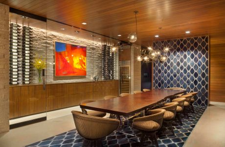 A modern, wood-paneled dining room with a large, vibrant artwork and a stunning chandelier.