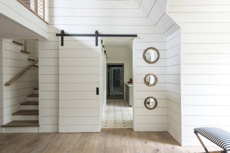 Elegant farmhouse interior with shiplap walls, sliding barn door, and rustic mirrors.