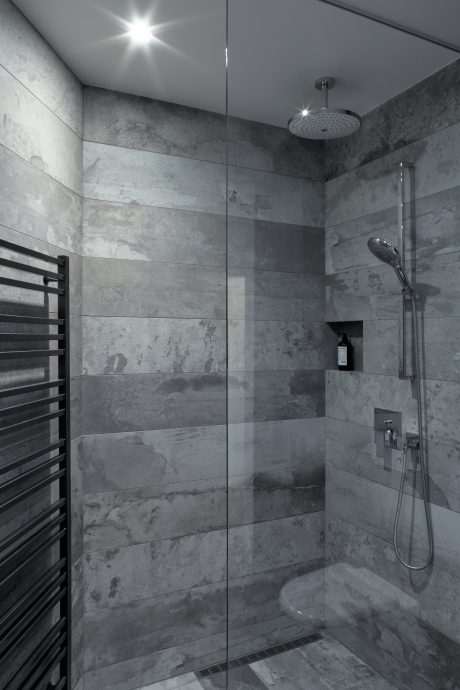 Modern bathroom design with grey marble tiles, rain shower, and towel warmer.