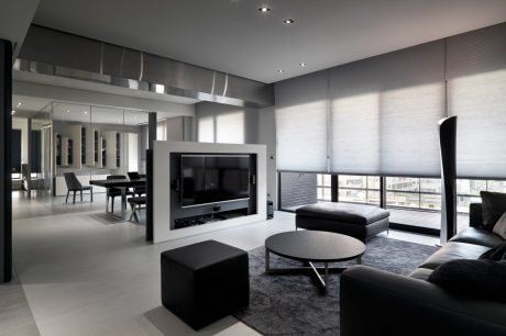 Modern, minimalist interior with sleek furniture, large TV, and expansive windows.