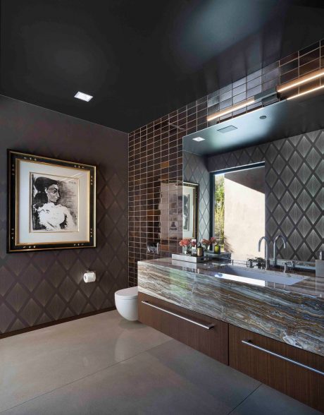 Modern bathroom with geometric wall tiles, marble vanity, and statement artwork.