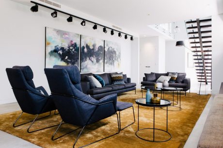 Sleek, modern living space with plush navy furnishings, geometric light fixtures, and abstract artwork.