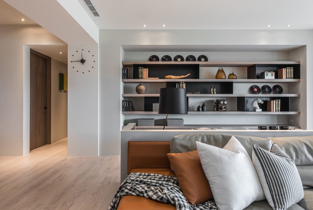 Minimalist open-concept living space with built-in wall shelving unit and cozy seating.