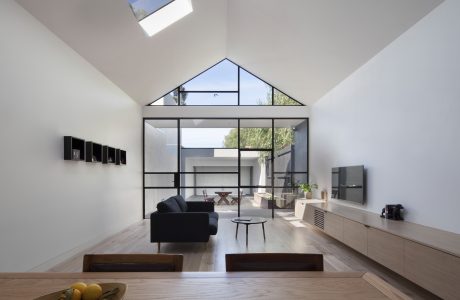 Open-plan living space with high ceilings, large windows, and modern furniture.