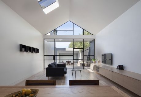 Open-plan living space with high ceilings, large windows, and modern furniture.