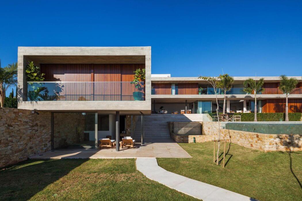 Modern beachside villa with timber-clad facade, expansive terrace, and lush landscaping.