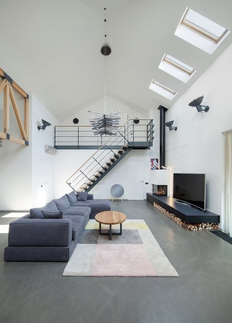 Minimalist living space with angular stairs, fireplace, and distinctive lighting fixtures.