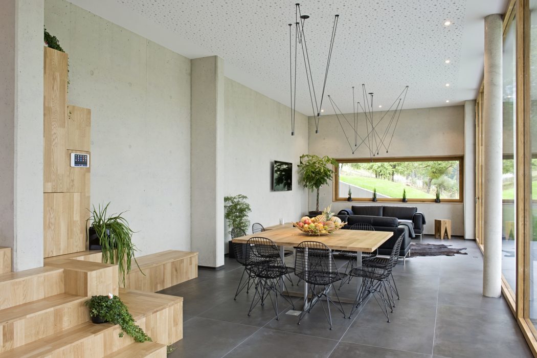 Spacious, modern dining area with concrete floors, wooden table, and industrial lighting.