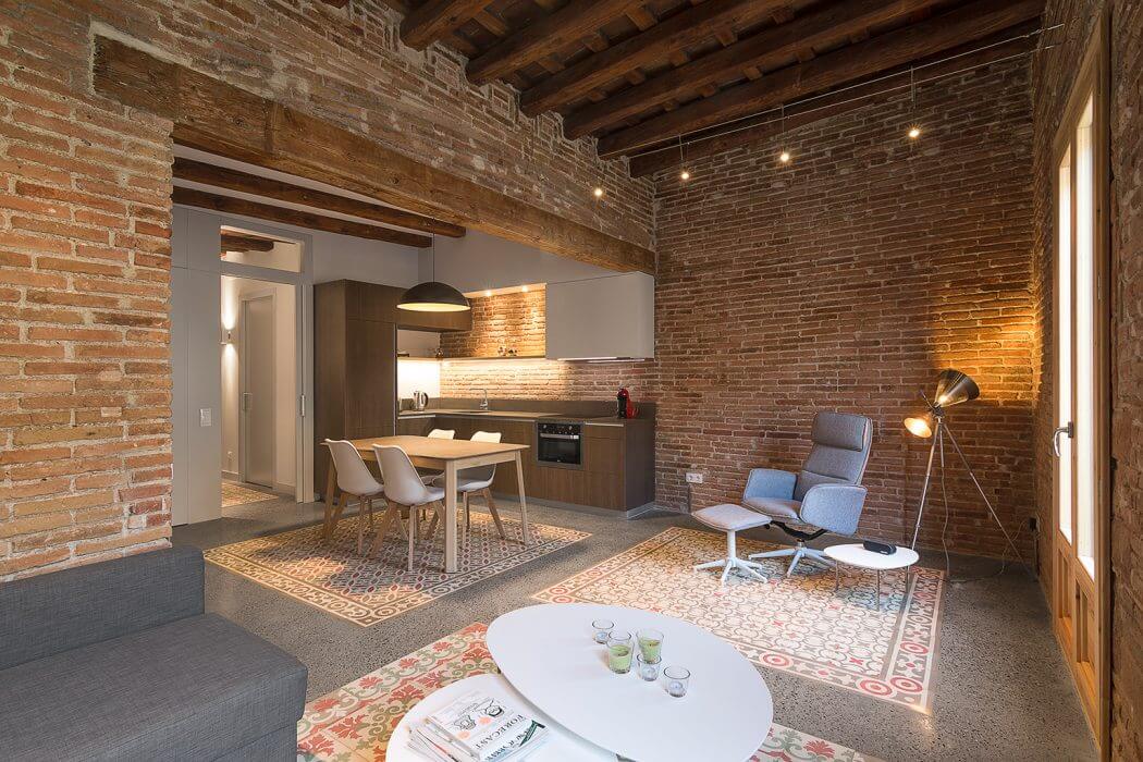 Cozy open-plan apartment with exposed brick walls, wood beams, and contemporary furnishings.