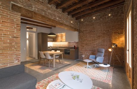 Cozy open-plan apartment with exposed brick walls, wood beams, and contemporary furnishings.