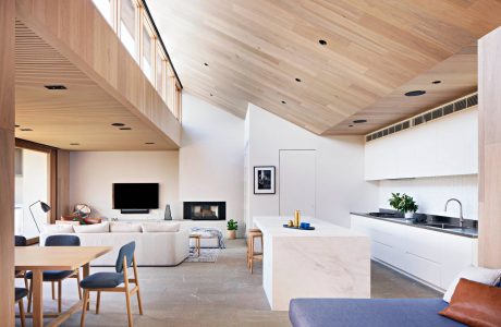 Spacious open-plan living area with high-ceilinged wooden beams, modern kitchen, and cozy seating.