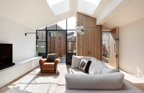 Modern, spacious living room with high ceilings, wood paneling, and large windows providing natural light.