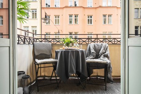 A cozy balcony with a table set for a meal, framed by a quaint residential building.