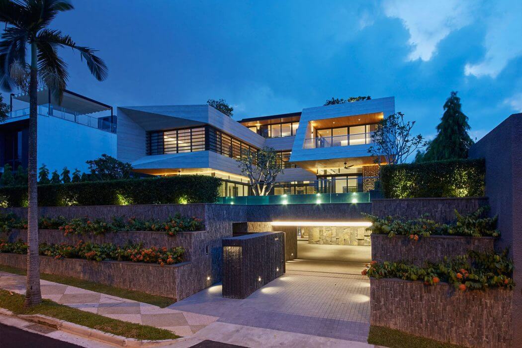 A modern, multi-level residential structure with clean lines, lush landscaping, and subtle lighting.