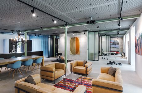 Modern, open-concept office with industrial-style lighting, bold artwork, and cozy lounge area.