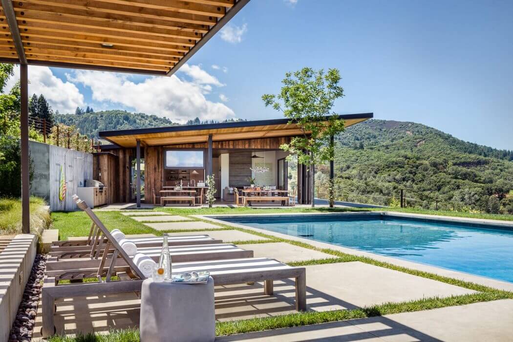 Rustic yet modern wooden structure with covered patio, pool, and scenic mountain views.