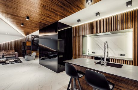 Modern kitchen with sleek wooden paneling, black accents, and a marble backsplash.