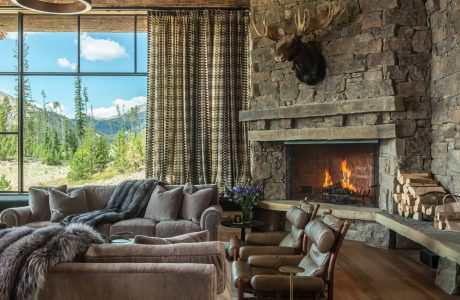 Rustic living room with stone fireplace, wooden beams, and cozy furnishings.