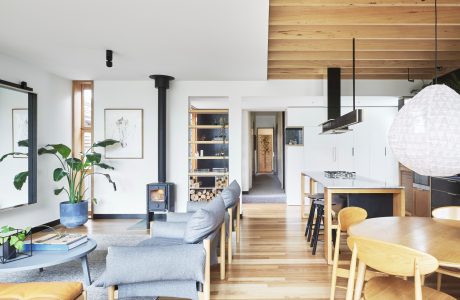 Cozy open-concept living space with wooden accents, modern furniture, and a wood-burning stove.