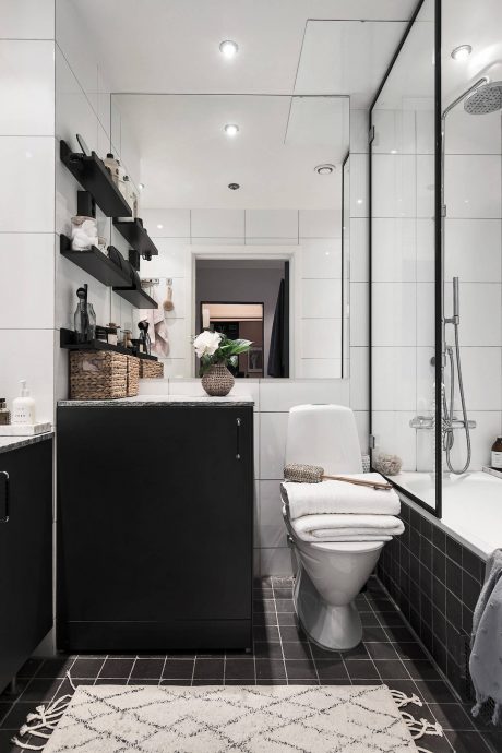 Sleek, modern bathroom with minimalist black and white design, open shelves, and patterned rug.