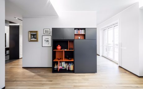 Modern and minimalist living room with sleek black built-in storage unit and natural wood flooring.