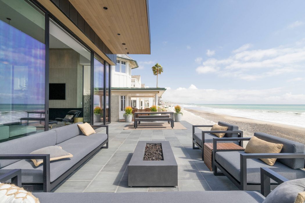 Sleek outdoor patio with modern furniture, fire pit, and stunning ocean view.