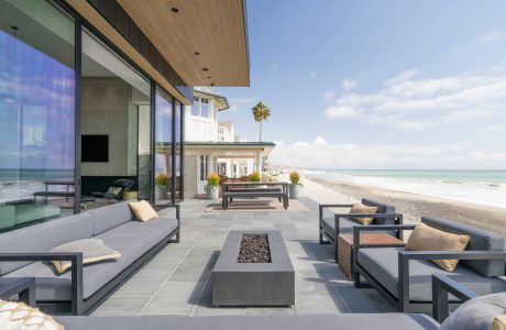 Sleek outdoor patio with modern furniture, fire pit, and stunning ocean view.