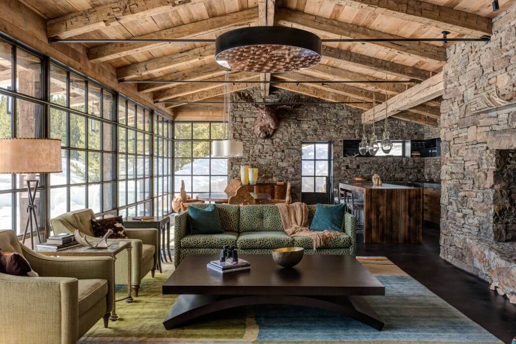 Rustic cabin interior featuring exposed wooden beams, stone walls, and modern furnishings.