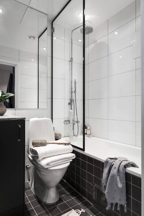 A modern, minimalist bathroom with sleek tile, a showerhead, and neatly folded towels.