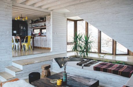 Rustic, modern interior with exposed wood beams, large windows, and eclectic decor.