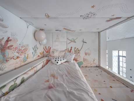 Whimsical, nature-inspired mural on wall; playful lighting and decor in cozy bedroom.