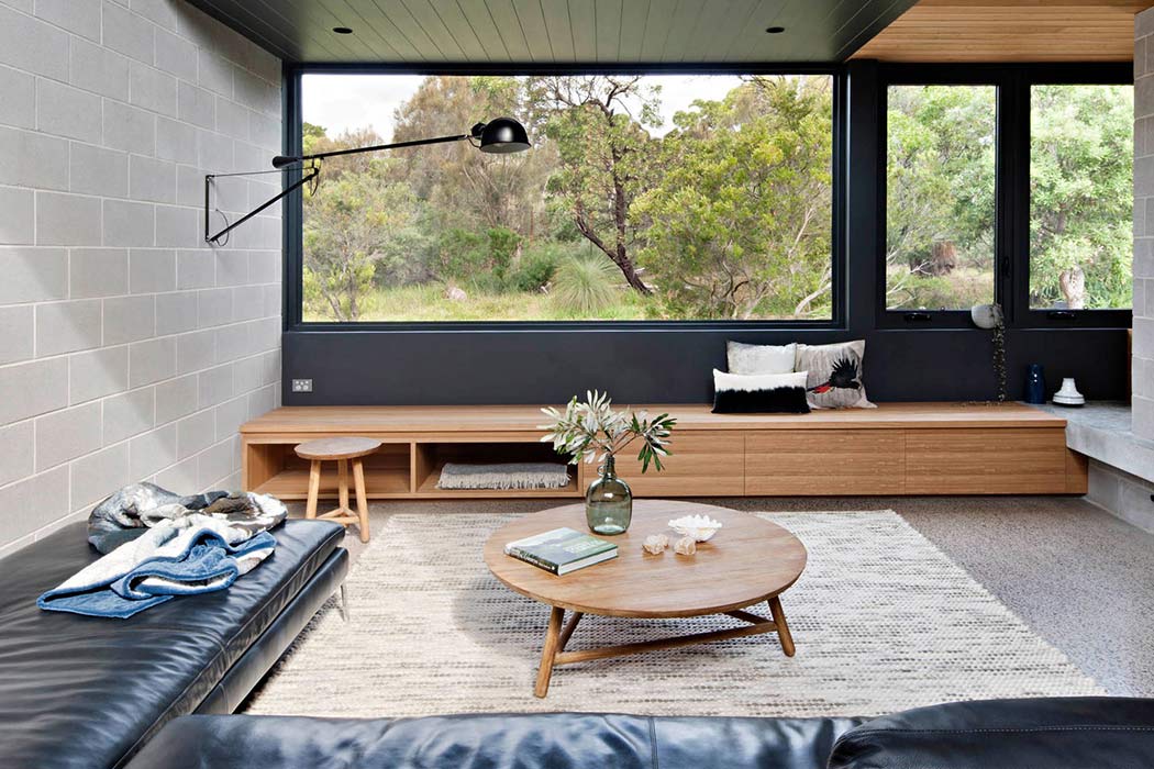A modern living space with a wall-mounted bookshelf, large windows, and a wooden coffee table.