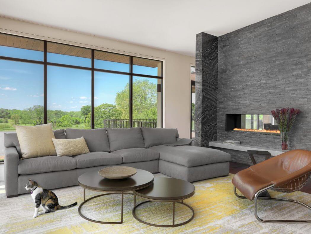 Spacious modern living room with floor-to-ceiling windows, gray sectional, and stone fireplace.