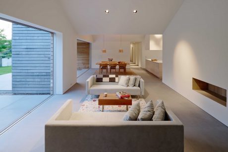 Spacious open-plan living area with large windows, modern furniture, and a cozy fireplace.