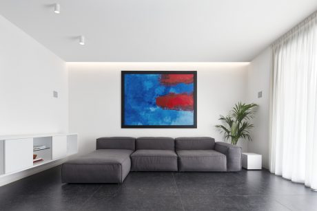 Minimalist living room with gray modular sofa, large abstract artwork, and potted plant.