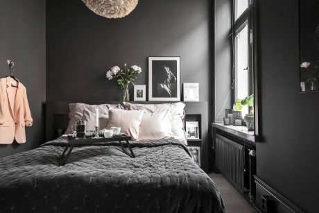 A cozy, monochromatic bedroom with plush bedding, stylish lighting, and framed artwork.