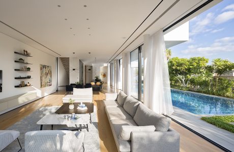 Spacious living room with sliding glass doors, outdoor pool, and lush greenery.