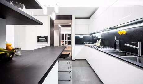 Sleek, modern kitchen featuring a dark countertop, minimalist white cabinetry, and recessed lighting.