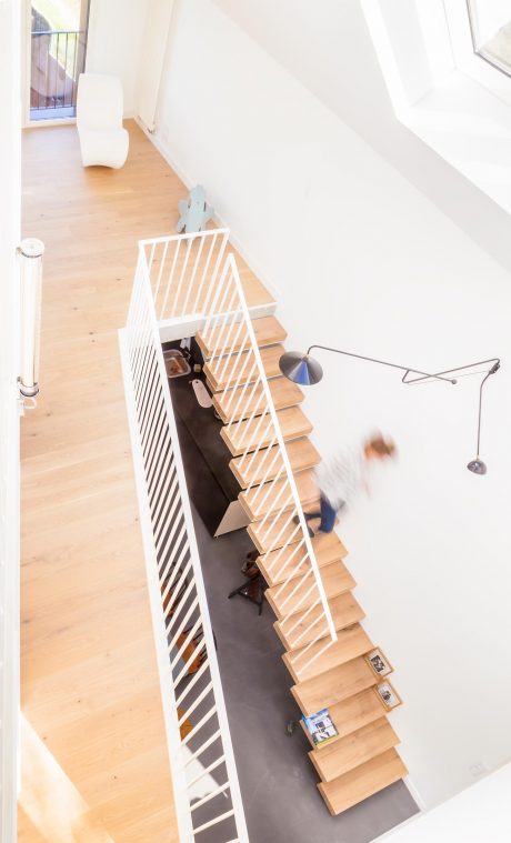 Elegant modern staircase with wooden steps and white metal railing; minimalist design.