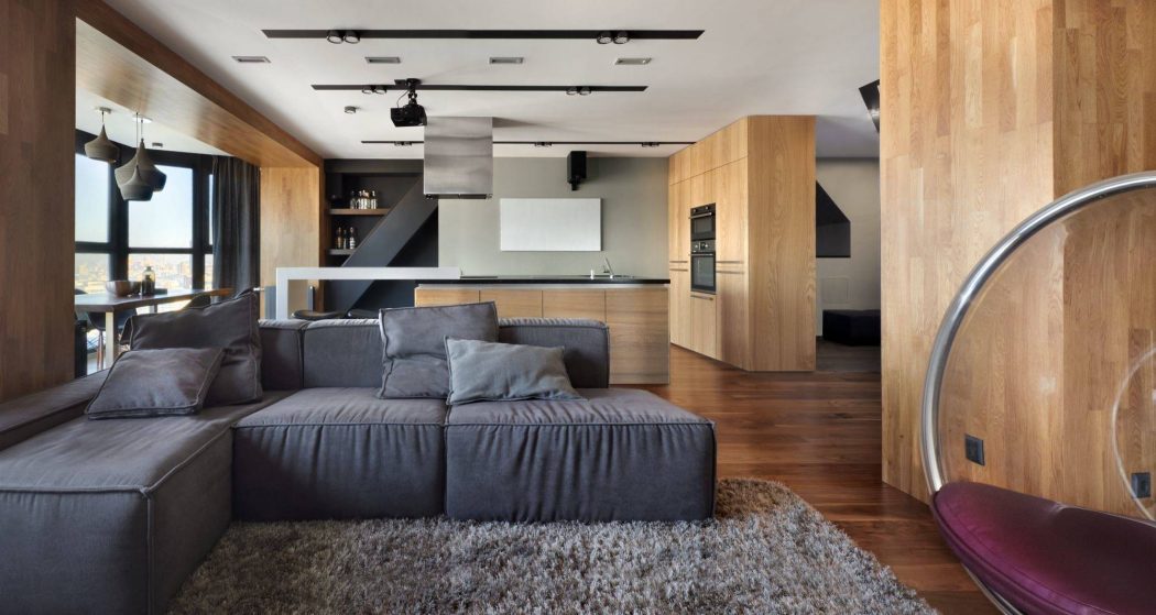 Sleek, modern interior with wooden accents, large sectional sofa, and recessed lighting.