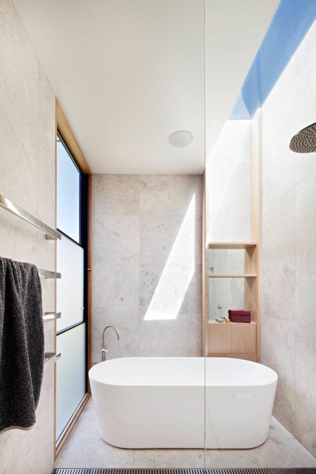 Sleek, minimalist bathroom design with freestanding tub, marble walls, and built-in shelving.