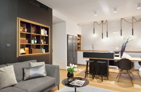 Modern open-concept living space with black accents, wood elements, and sleek kitchen design.