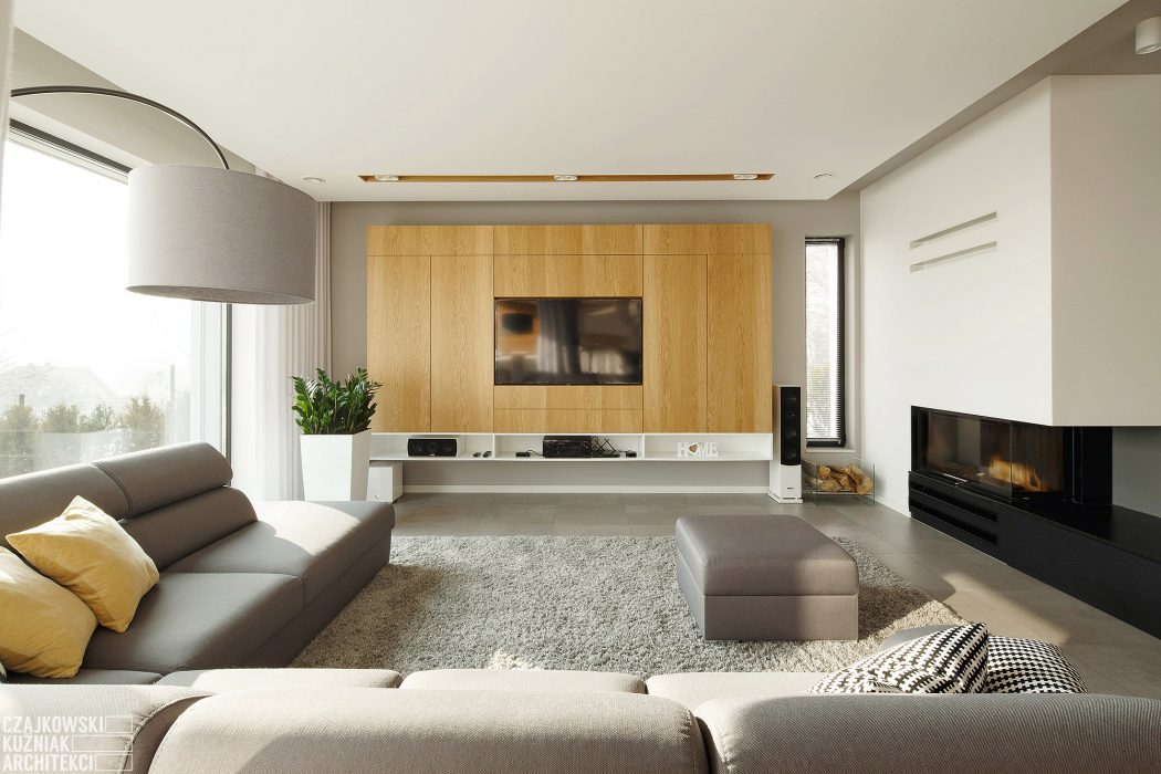 Elegant modern living room with wooden media unit, fireplace, and neutral furnishings.