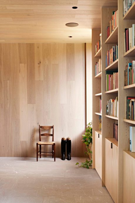 A cozy home library with wooden shelves, tiled floor, and a rustic chair.