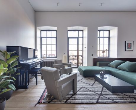 Spacious living room with arched windows, black piano, plush seating, and a vibrant area rug.